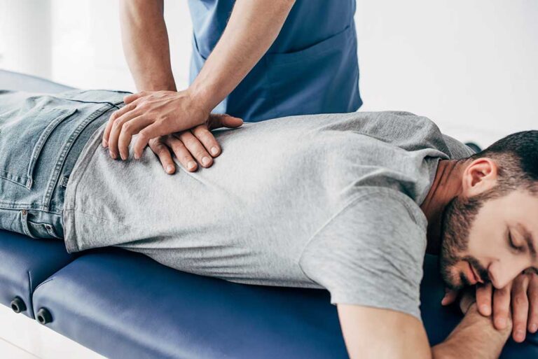 Clinician gently glides a smooth metal tool over a patient’s calf during a soft-tissue treatment session.